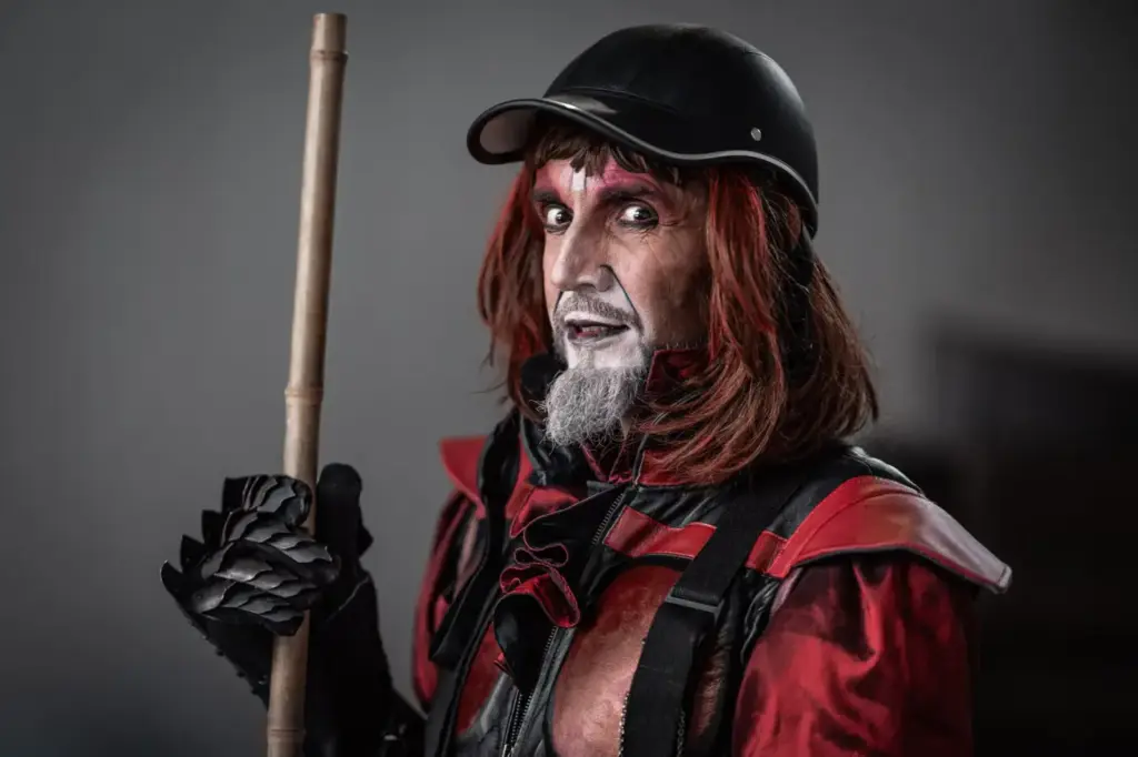 A dramatic street performer in a striking red and black costume with makeup