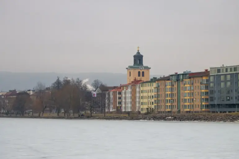 A serene winter view of Jönköping's lakeside with colorful buildings and a historic church