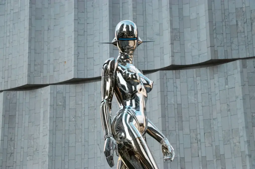 A sleek, chrome humanoid sculpture set before a minimalist, geometric wall