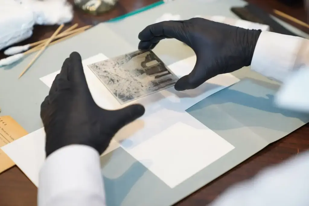 A specialist restoring an old photo using gloves and tools for careful preservation