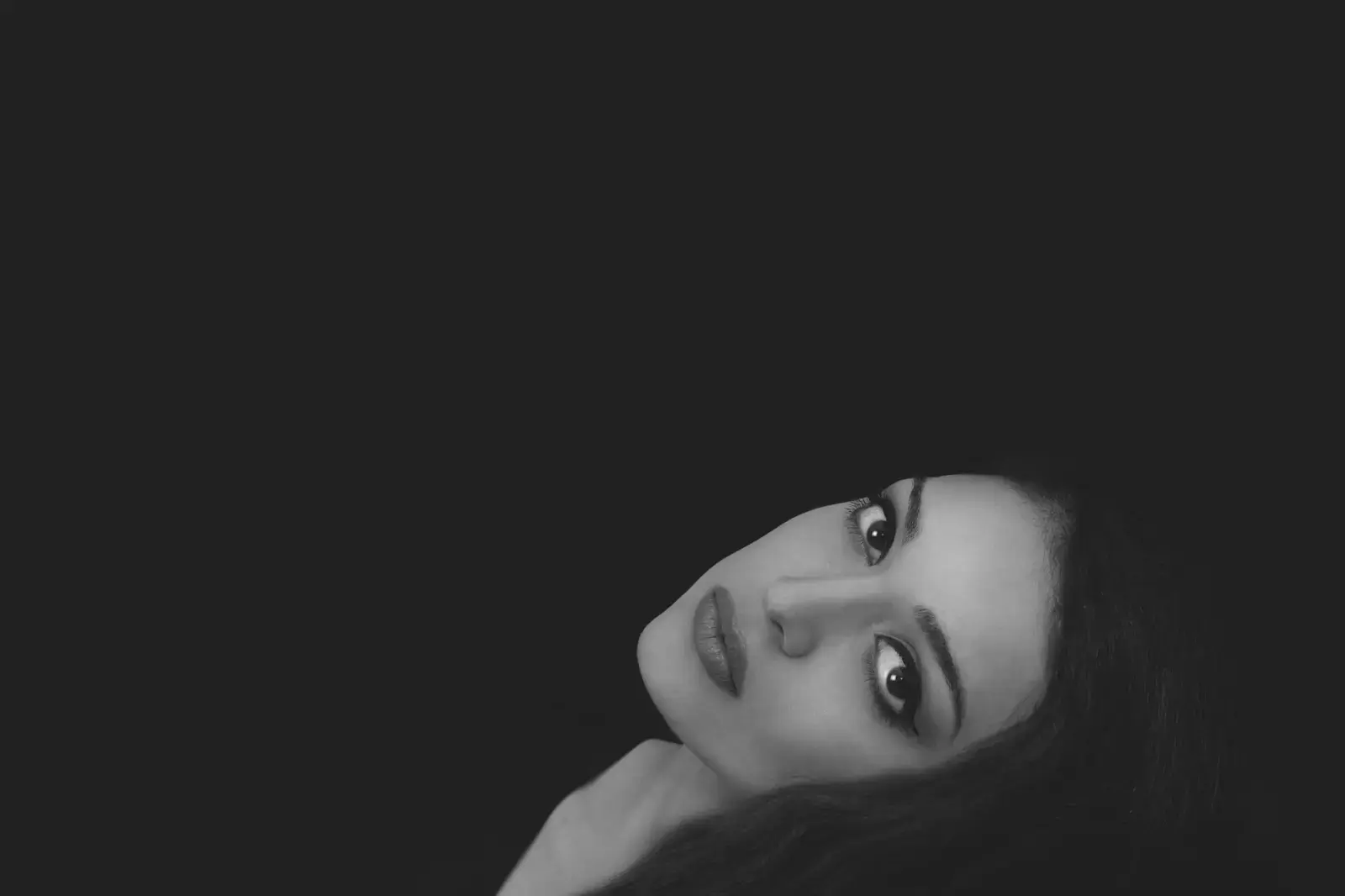 Tia Bajpai Swaps Pop Glitz for Dread in Eerie Video FANAA Black and white portrait of Tia Bajpai looking serious against a dark background