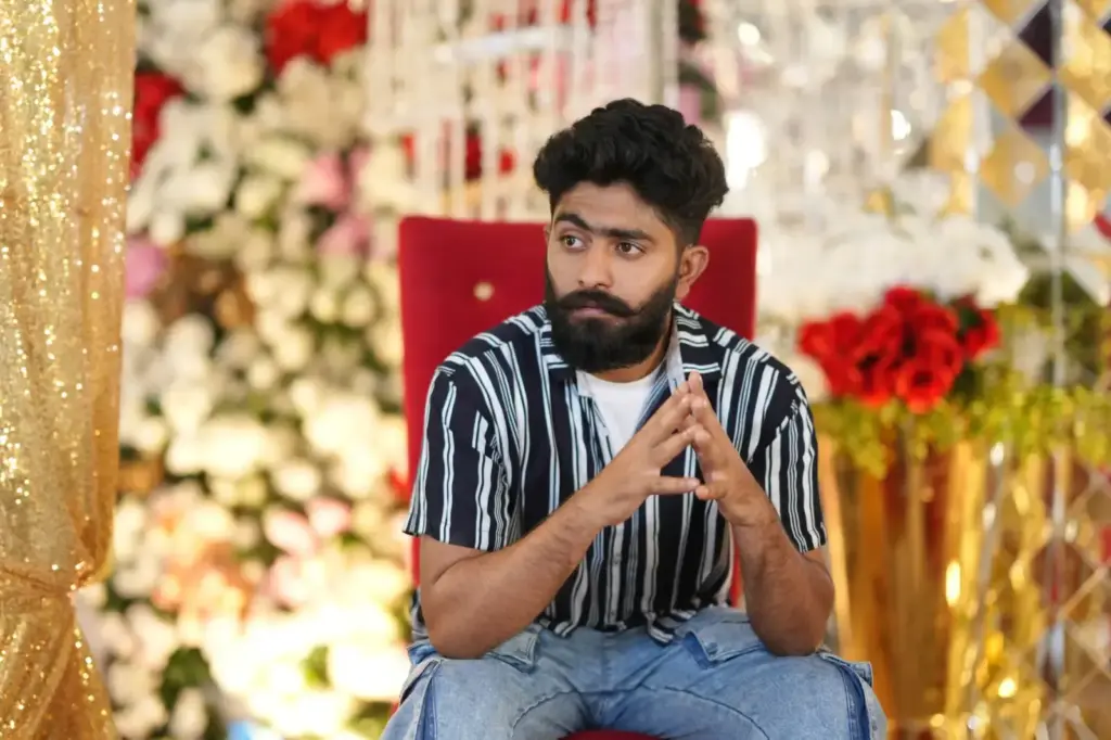 A thoughtful man with beard and mustache sitting in a colorful, festive setting