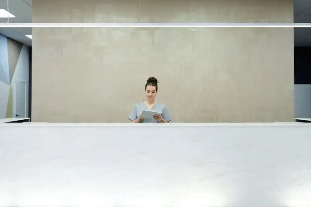 A woman receptionist using a tablet at a modern office reception desk