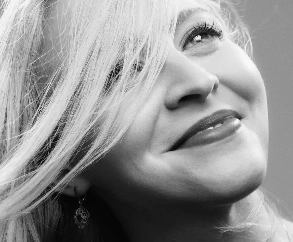 Close-up black and white portrait of a smiling woman with flowing hair, exuding elegance
