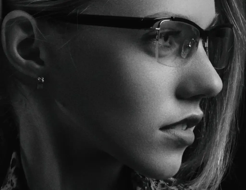 Close-up portrait of a woman wearing eyeglasses, captured in black and white