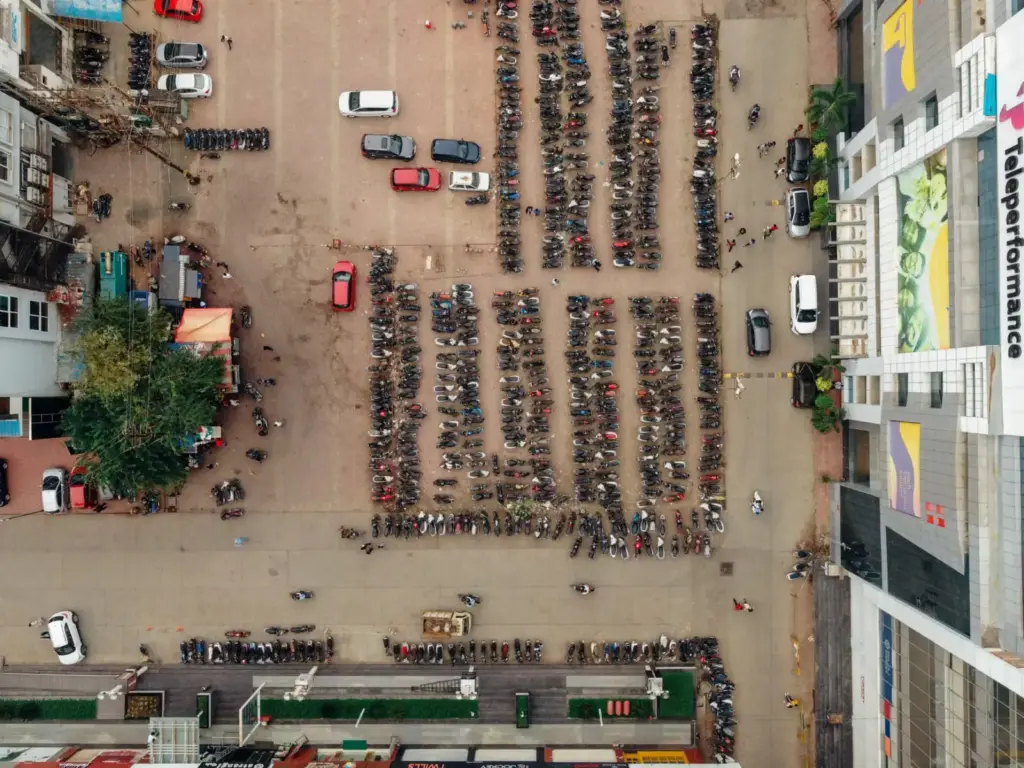 Drone shot capturing parked motorcycles and cars in a busy urban parking lot