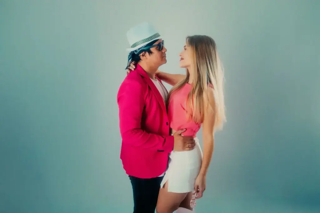 Elegant couple posing stylishly, wearing pink outfits against a neutral background
