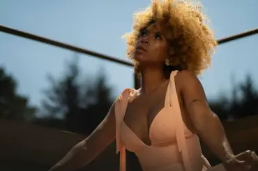 Woman with afro hairstyle in a peach dress smiling outdoors in natural light