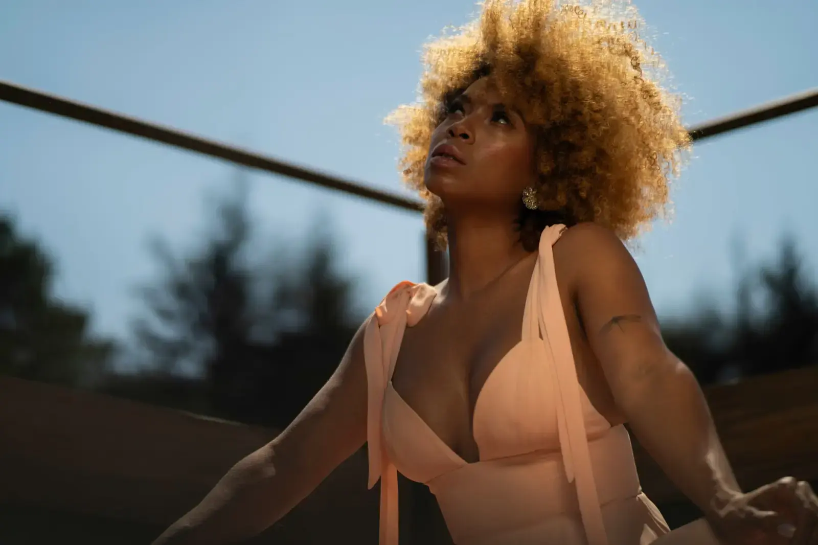 Halle Berry Calls Zendaya Her ‘Sweetheart’ and Wants a Co-Star Role Woman with afro hairstyle in a peach dress smiling outdoors in natural light