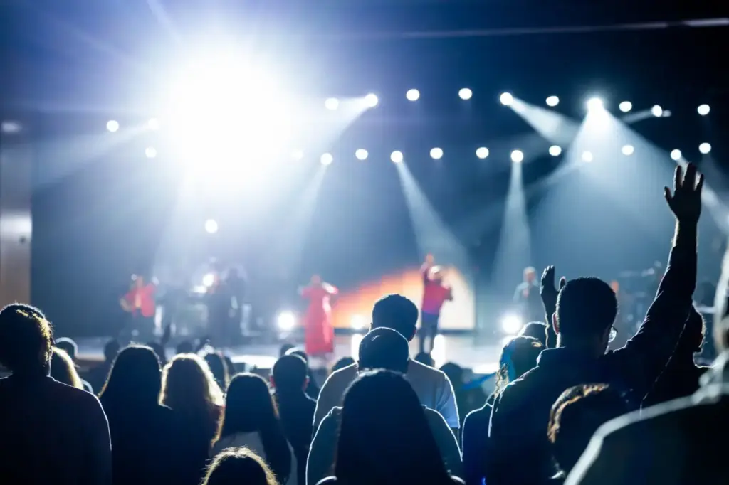 Energetic concert crowd with bright stage lights, capturing a lively atmosphere