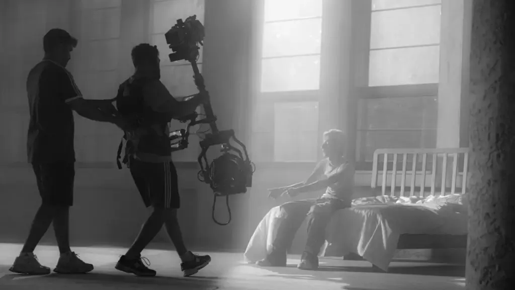Filmmakers using camera rig for artistic shot in moody setting with dramatic lighting