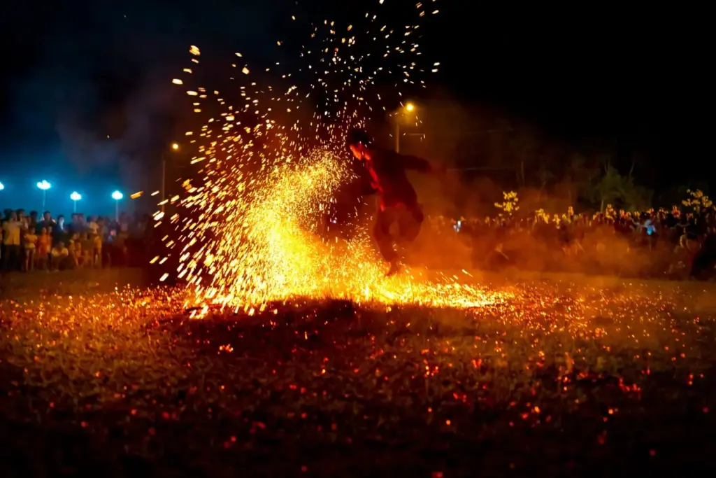 Full body of male dancer performing dangerous movement with fire sparks at night among people