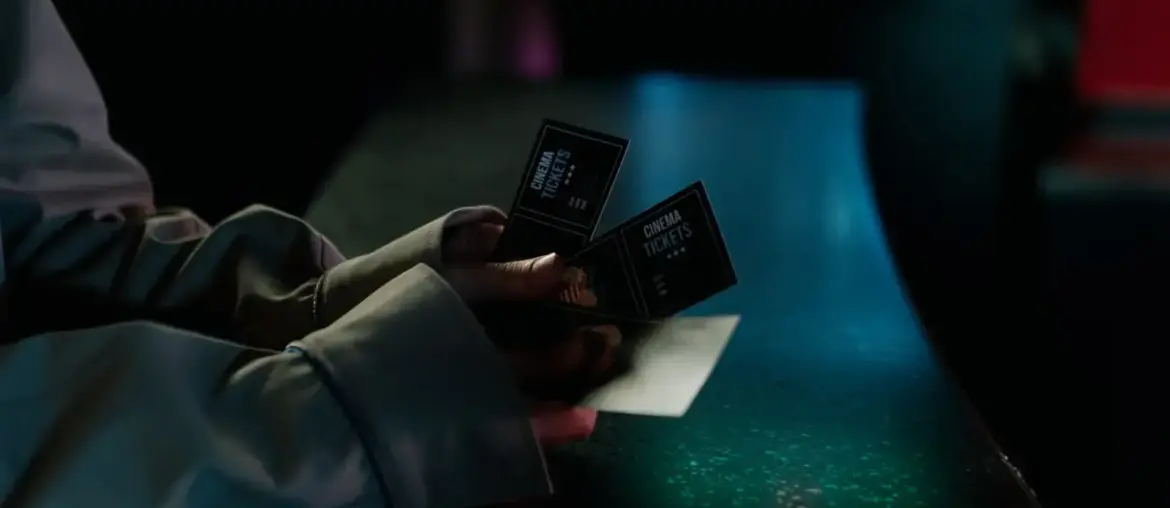 Moody image of a person holding cinema tickets at night, highlighting anticipation of a movie night