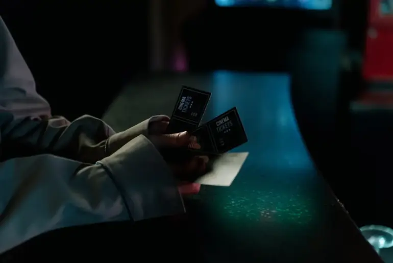 Moody image of a person holding cinema tickets at night, highlighting anticipation of a movie night