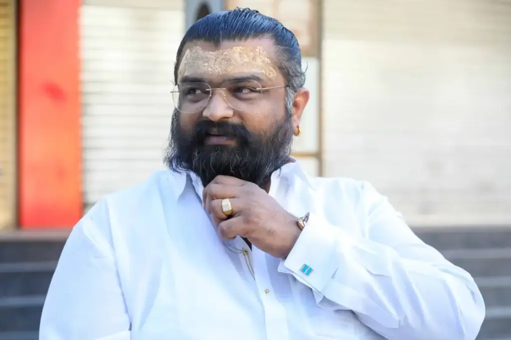 Portrait of a confident adult man with a beard and spectacles, wearing a white shirt outdoors