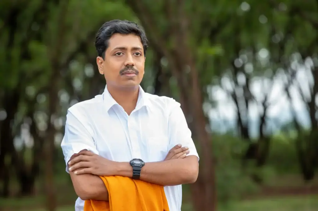 Portrait of a confident man with arms crossed, standing outdoors in a natural setting