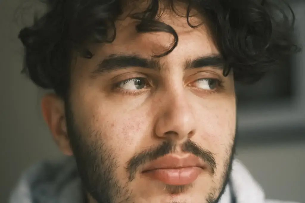 Portrait of a man with curly hair and a beard looking off to the side, in a reflective pose