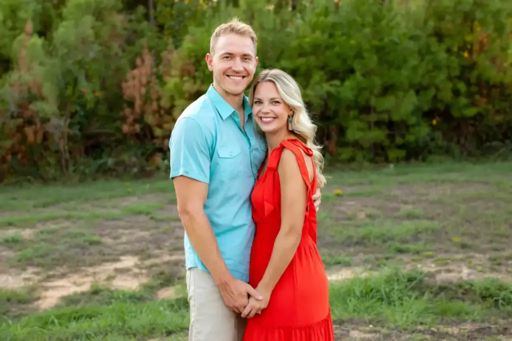 Smiling couple embracing in a sunny meadow setting, showcasing love and joy