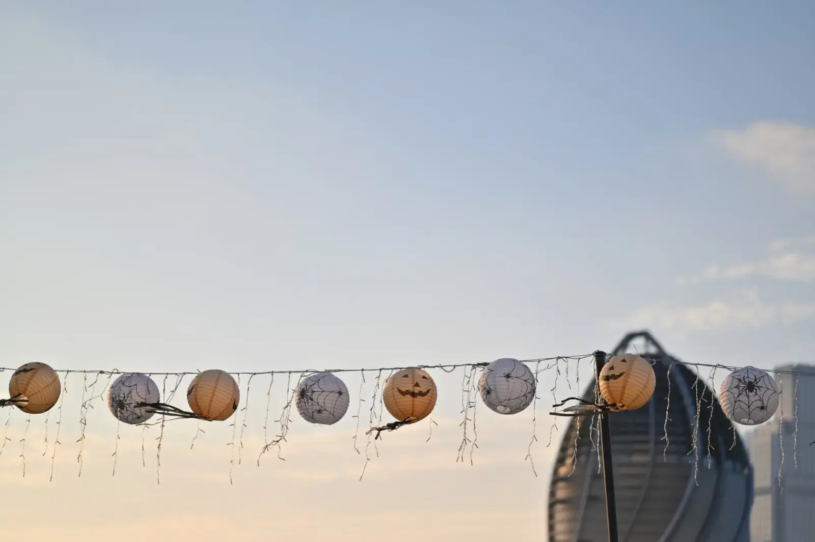 Lanterns Ep 6 Twist: Why Hal Jordan Had to Be Dug Up String lights with Halloween lanterns hanging outdoors against a city skyline in the evening