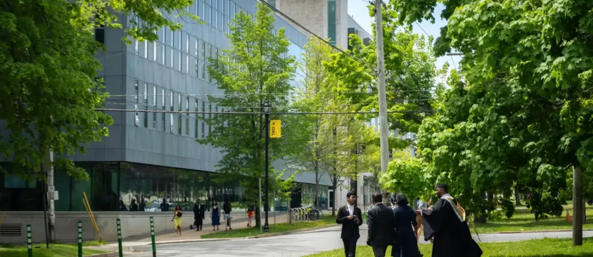 Students in graduation attire walking near a modern building in Halifax, NS, Canada