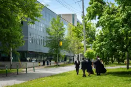 Students in graduation attire walking near a modern building in Halifax, NS, Canada