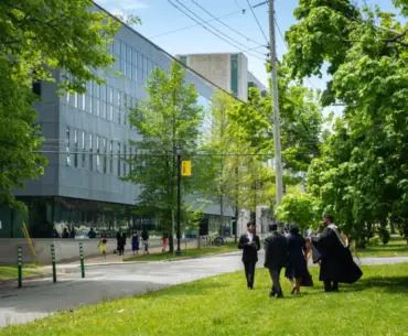 Students in graduation attire walking near a modern building in Halifax, NS, Canada