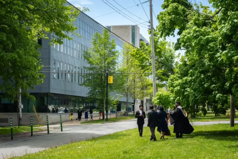 Students in graduation attire walking near a modern building in Halifax, NS, Canada