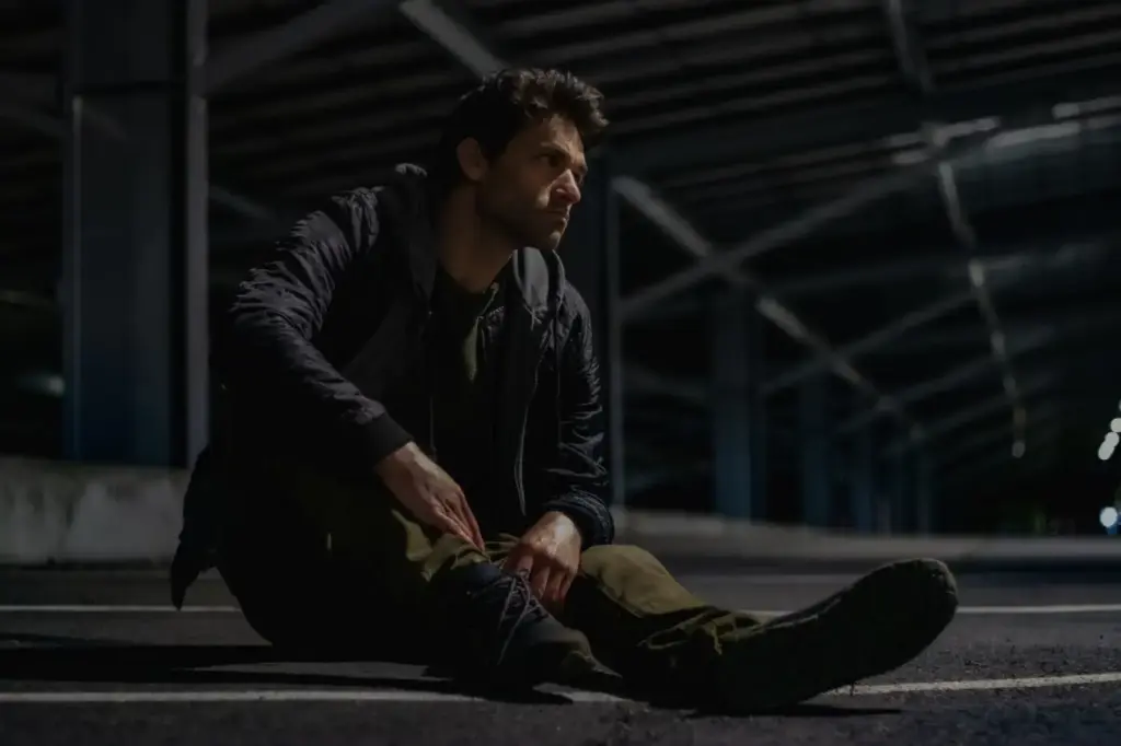 Thoughtful man sitting under a bridge at night, deep in reflection