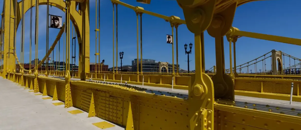 Vibrant yellow suspension bridge standing out against a clear blue sky, showcasing modern engineering