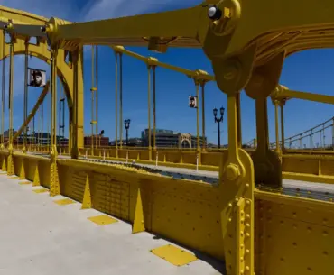 Vibrant yellow suspension bridge standing out against a clear blue sky, showcasing modern engineering
